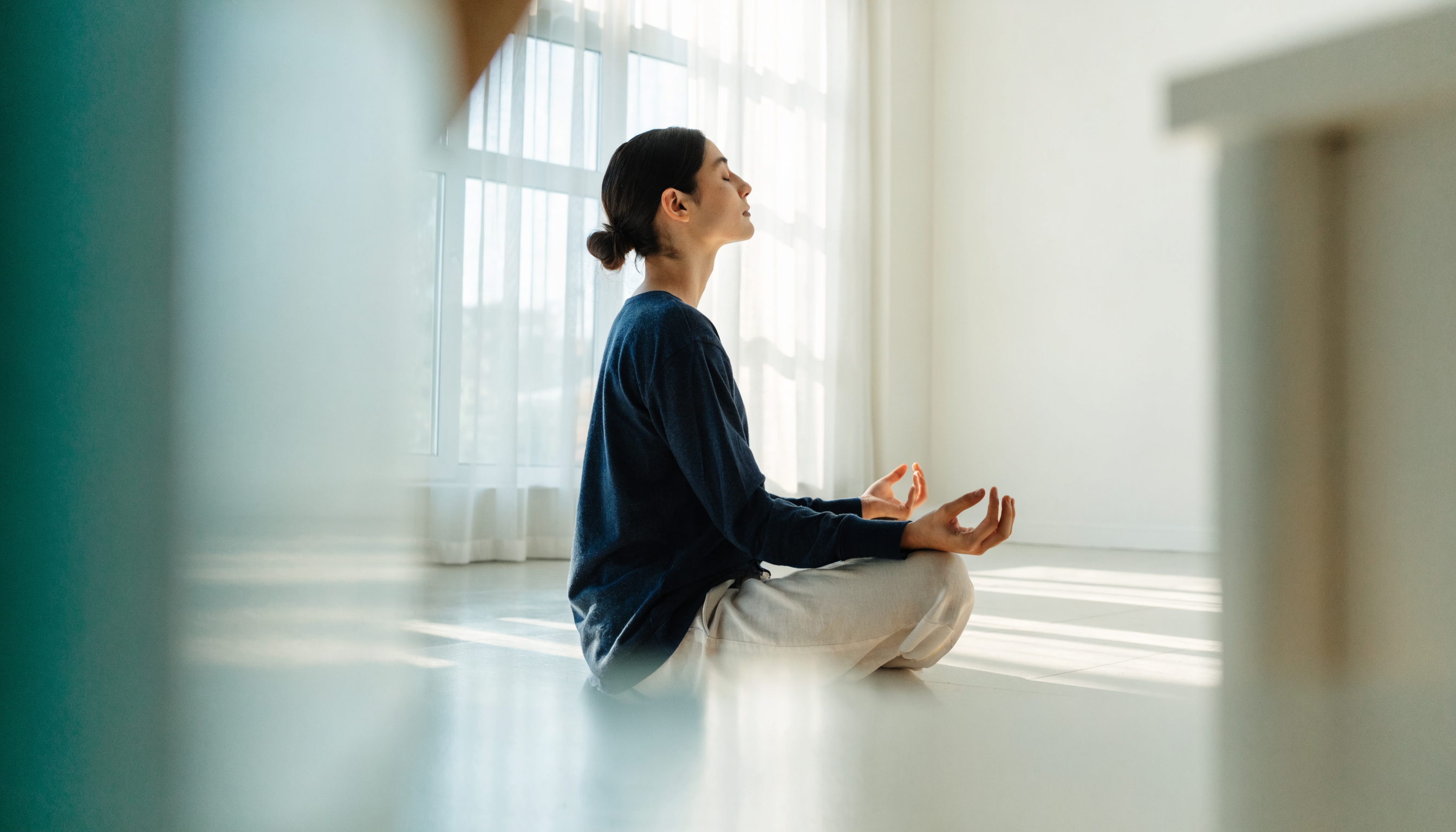 Person meditiert ruhig am Fenster – Cortisol senken